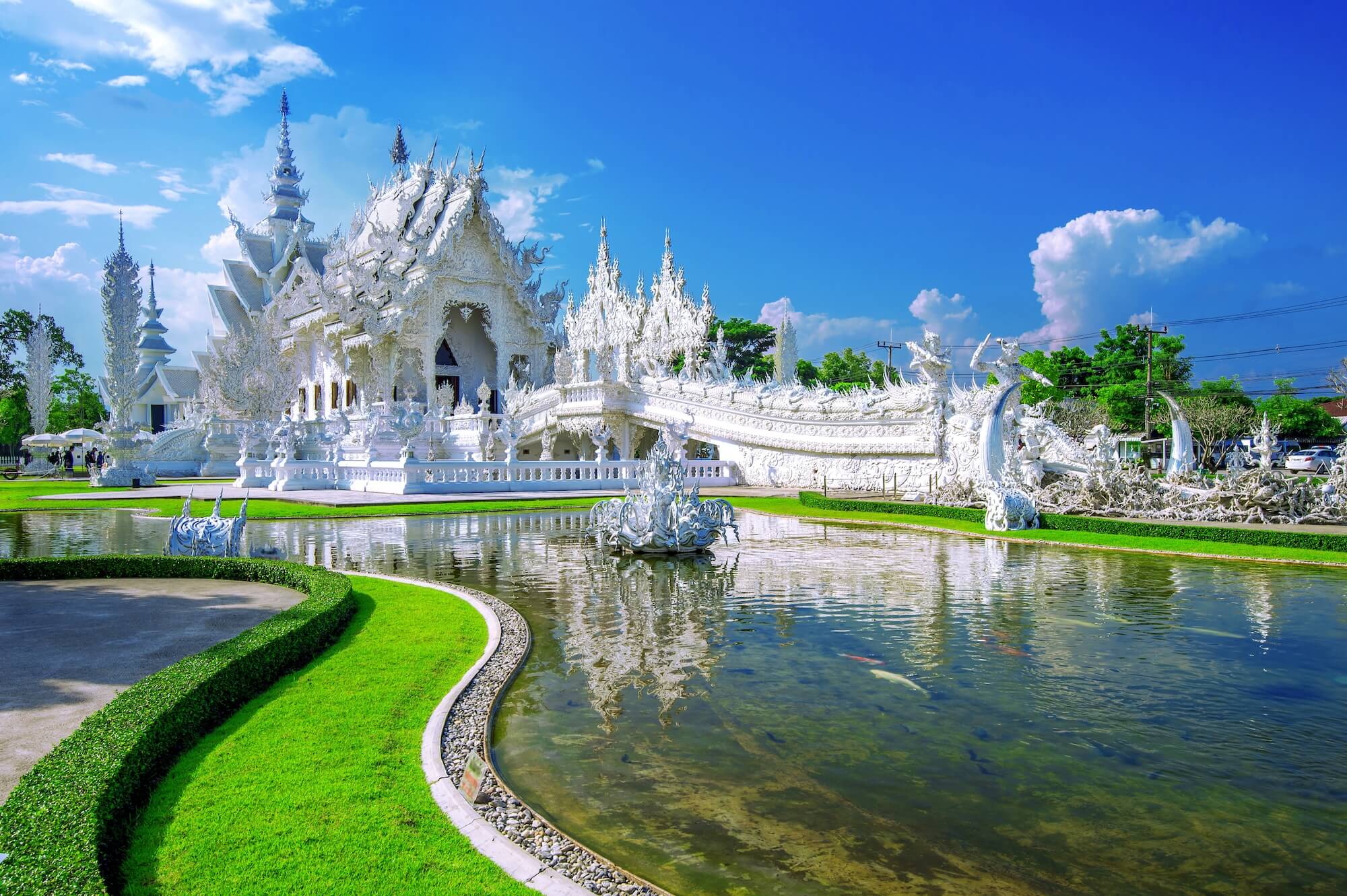 A grand temple known for its all-white exterior is covered in intricate plaster carvings and mirrored glass that reflects light.